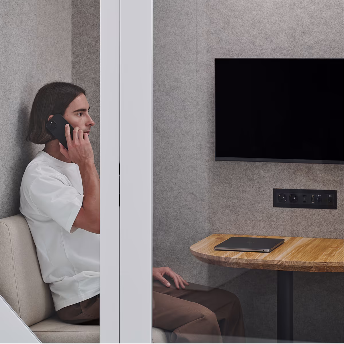 Person taking a phone call inside a soundproof office booth with acoustic panels