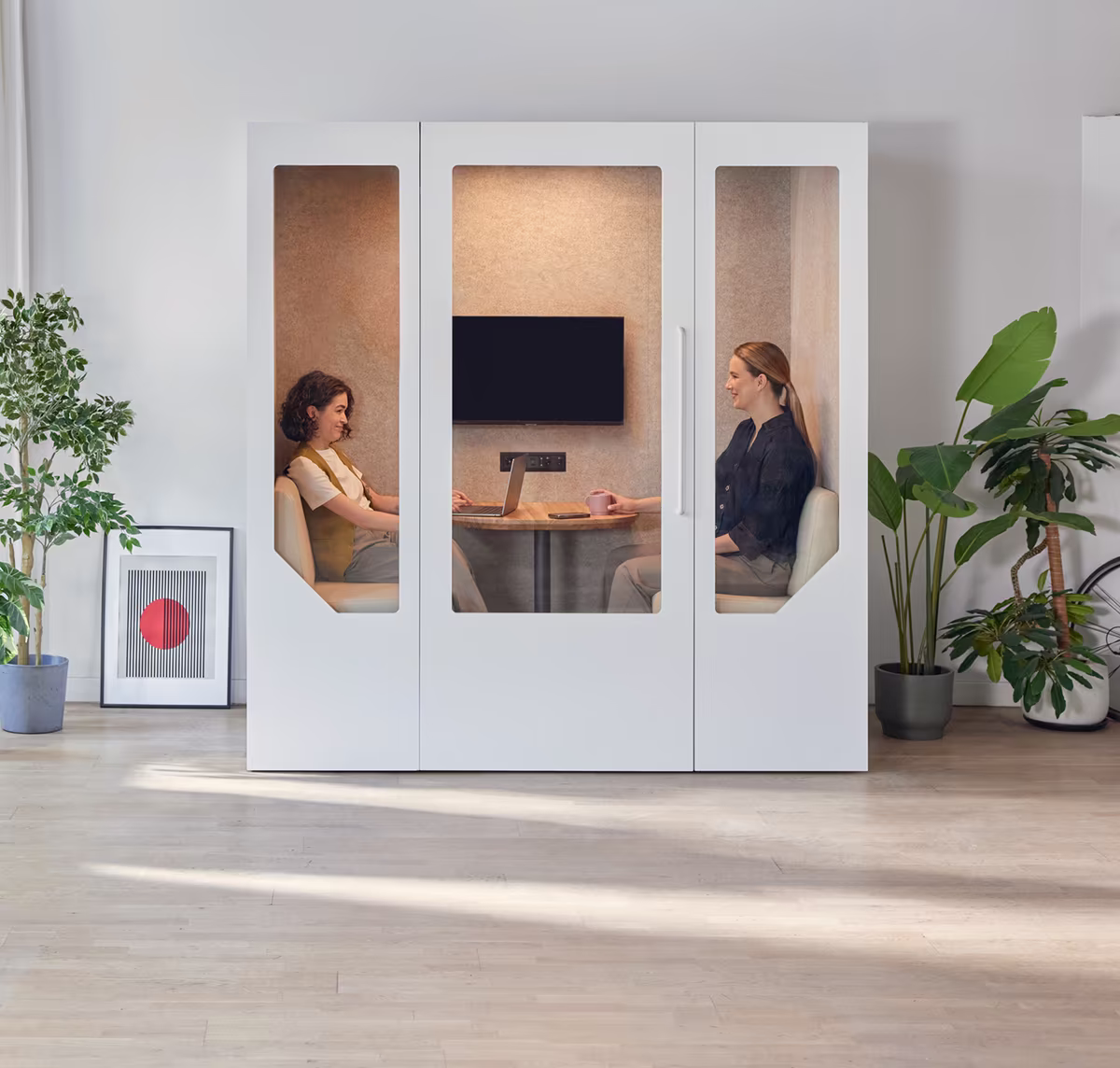 Two women having a private meeting inside a Persy soundproof booth in a bright modern office