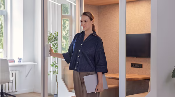 Female support agent opening a Persy booth door in a bright office environment