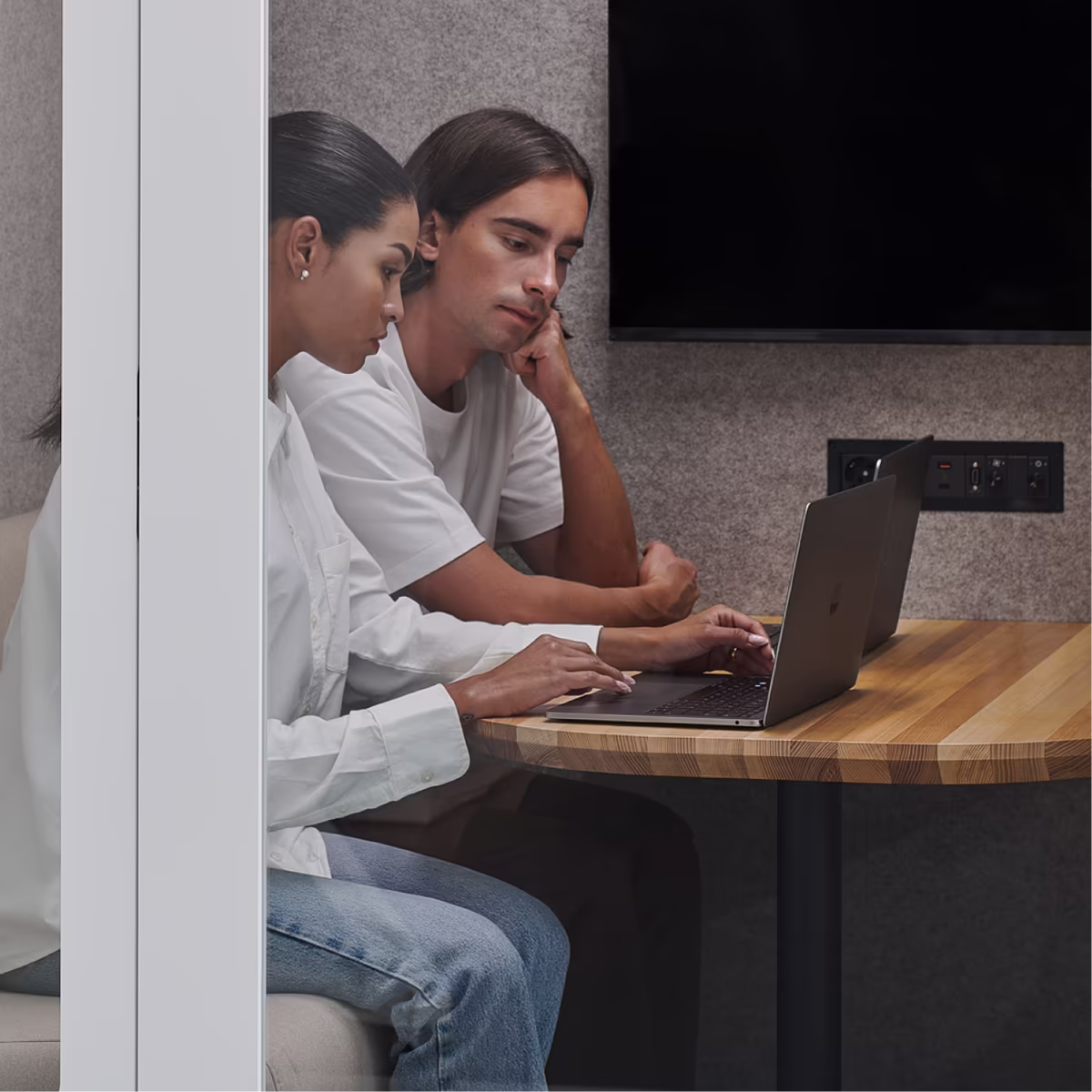 Two customer support agents working together on a laptop inside a Persy soundproof booth