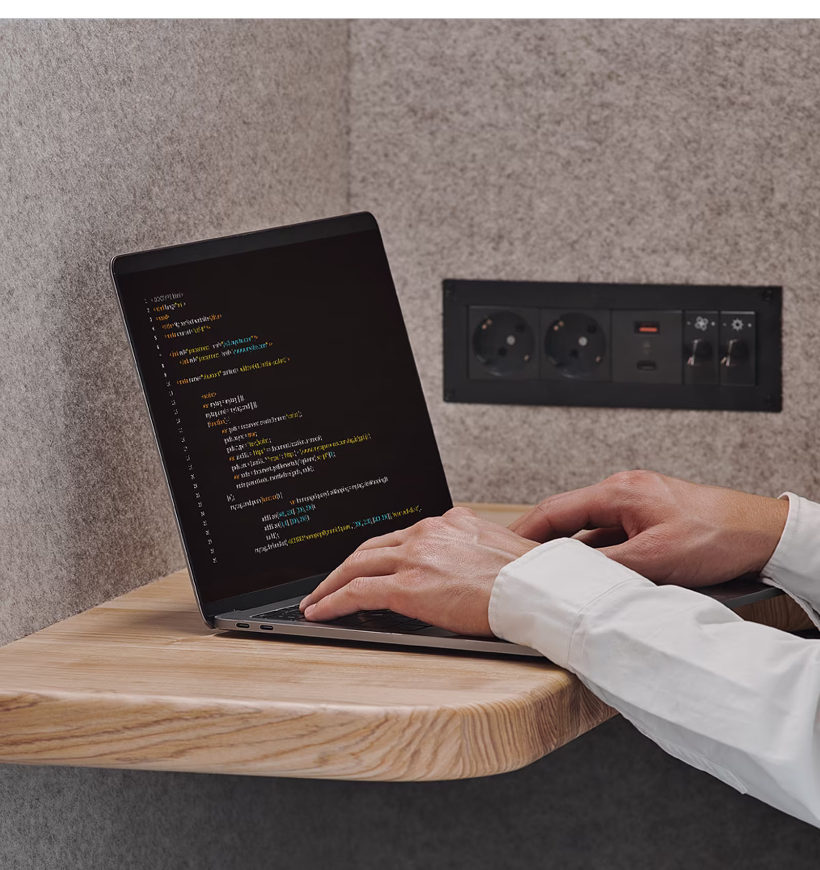 Developer coding on a laptop inside a Persy soundproof booth with a wooden desk