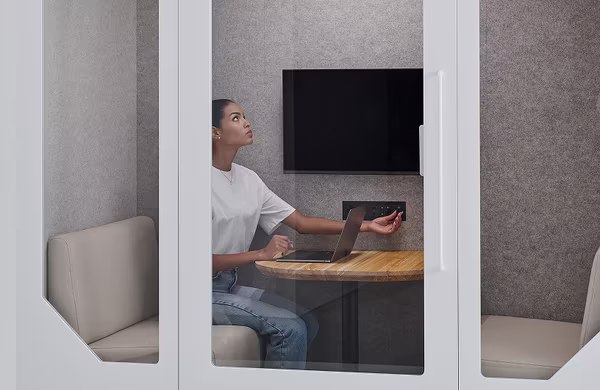 Member using a soundproof office booth for calls in a co-working space