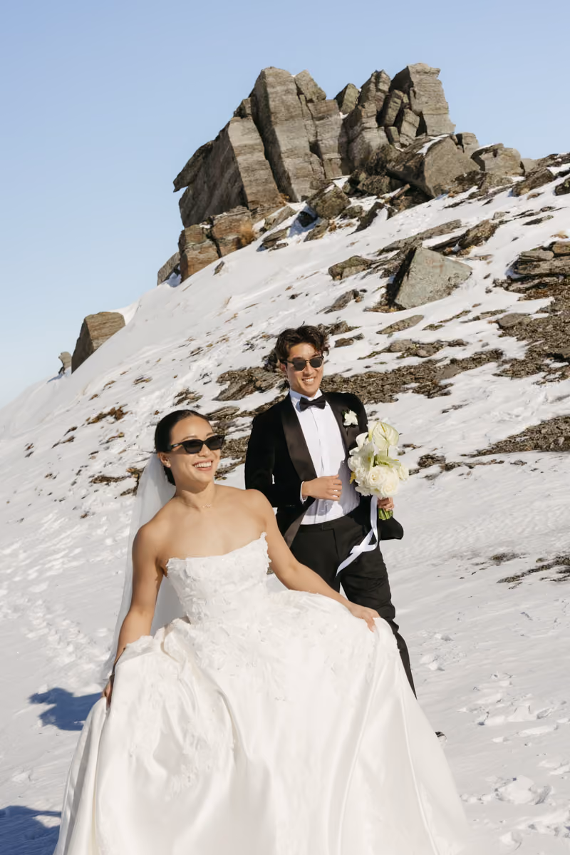 A couple just got married on a mountain in Queenstown in the winter. With snow covering the ground. A fun wedding shoot