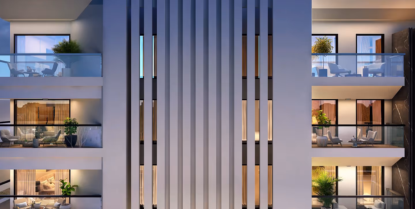 Modern apartment building facade with illuminated balconies and glass railings at dusk.