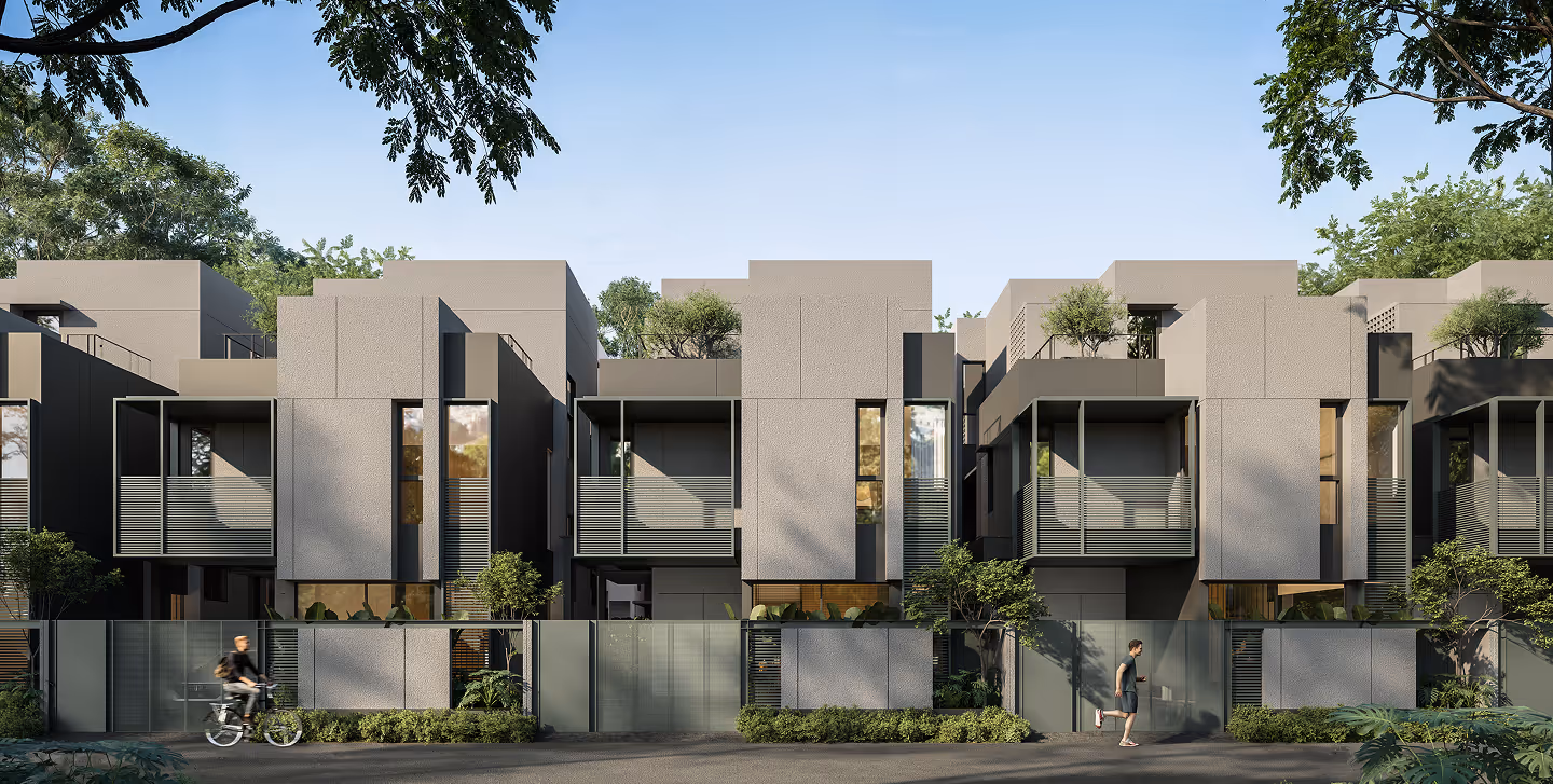 Modern gray townhouses with balconies, greenery, a cyclist, and a runner on a clear day.