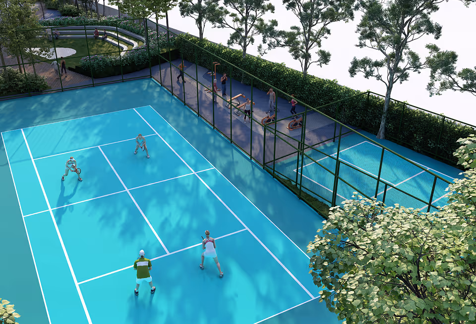 Two pairs playing doubles tennis on a blue court surrounded by trees and a fenced area with people exercising.