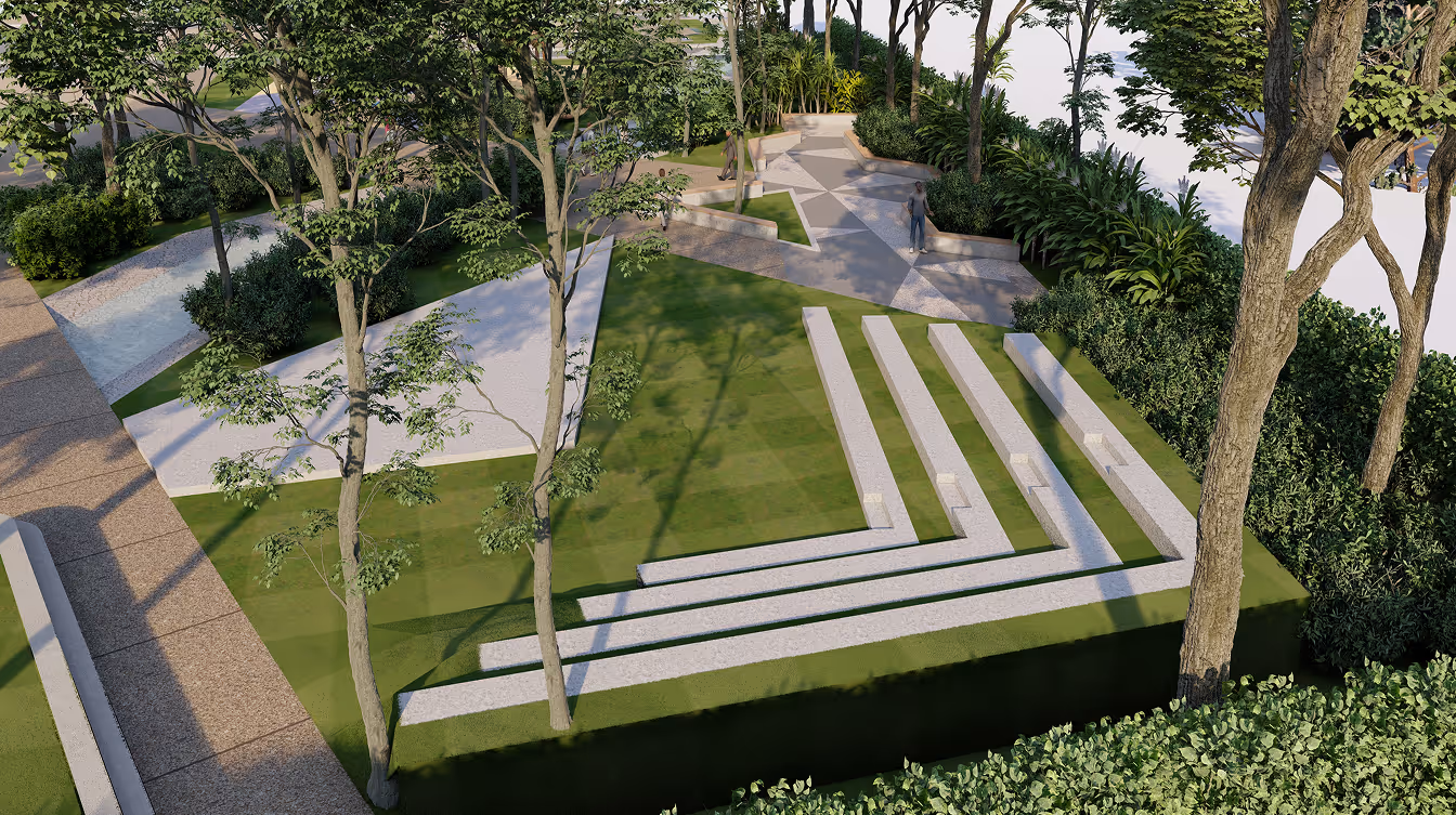 Outdoor park area with tiered white stone seating on grass and paved walkways surrounded by trees.