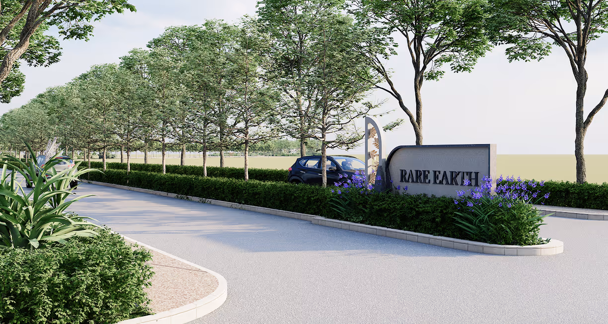 Entrance sign reading 'RARE EARTH' surrounded by greenery and purple flowers on a tree-lined road.