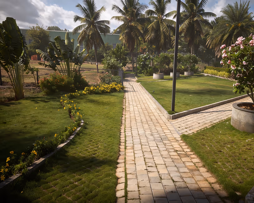 Sunlit garden path with green grass, palm trees, and flowering plants on a sunny day.