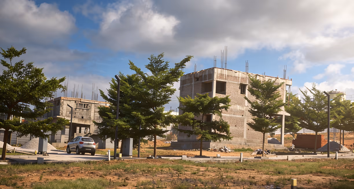 Partially built concrete houses surrounded by trees under a cloudy blue sky on a construction site.