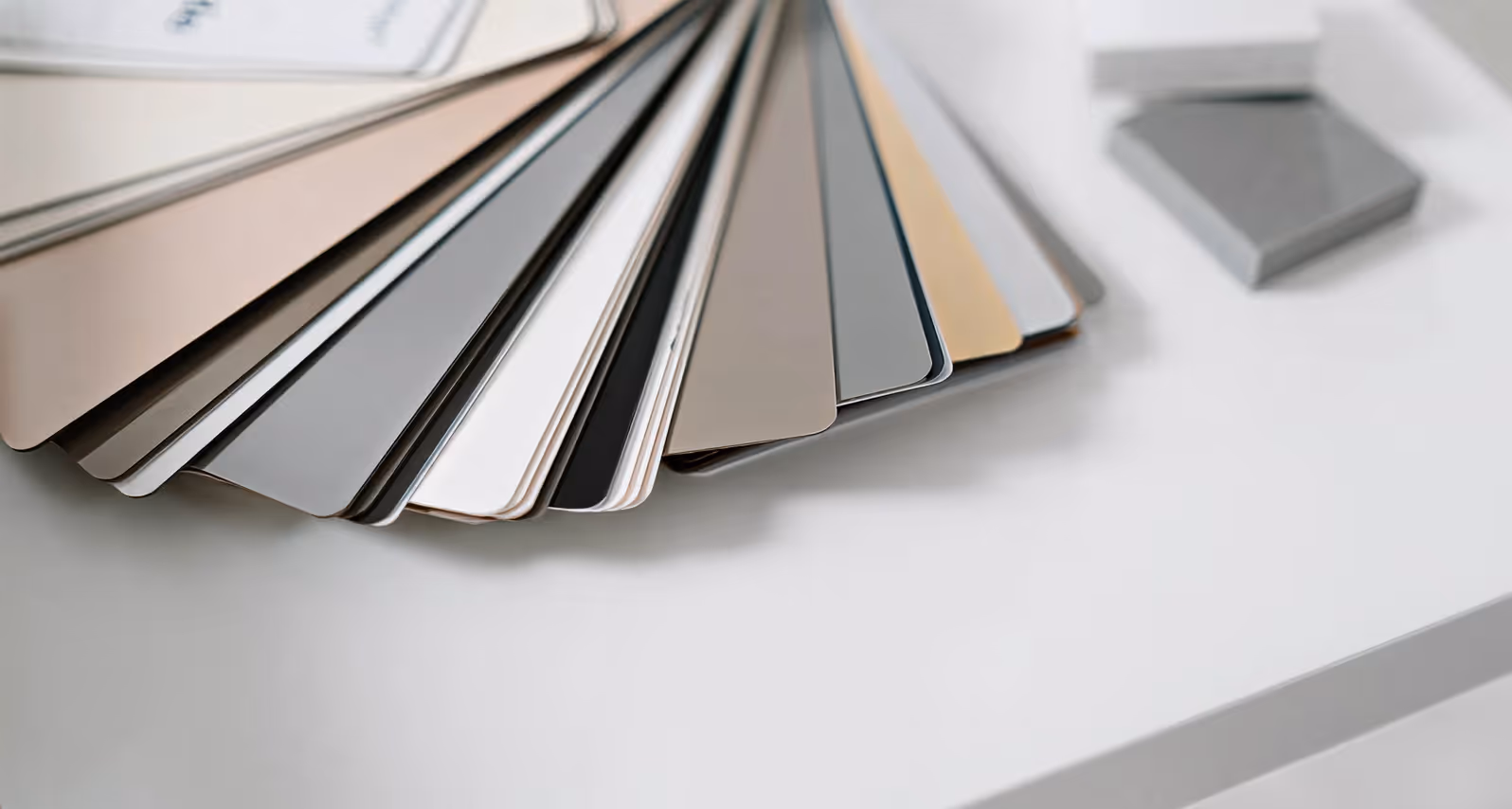 A fanned spread of color sample cards in neutral tones on a white surface.