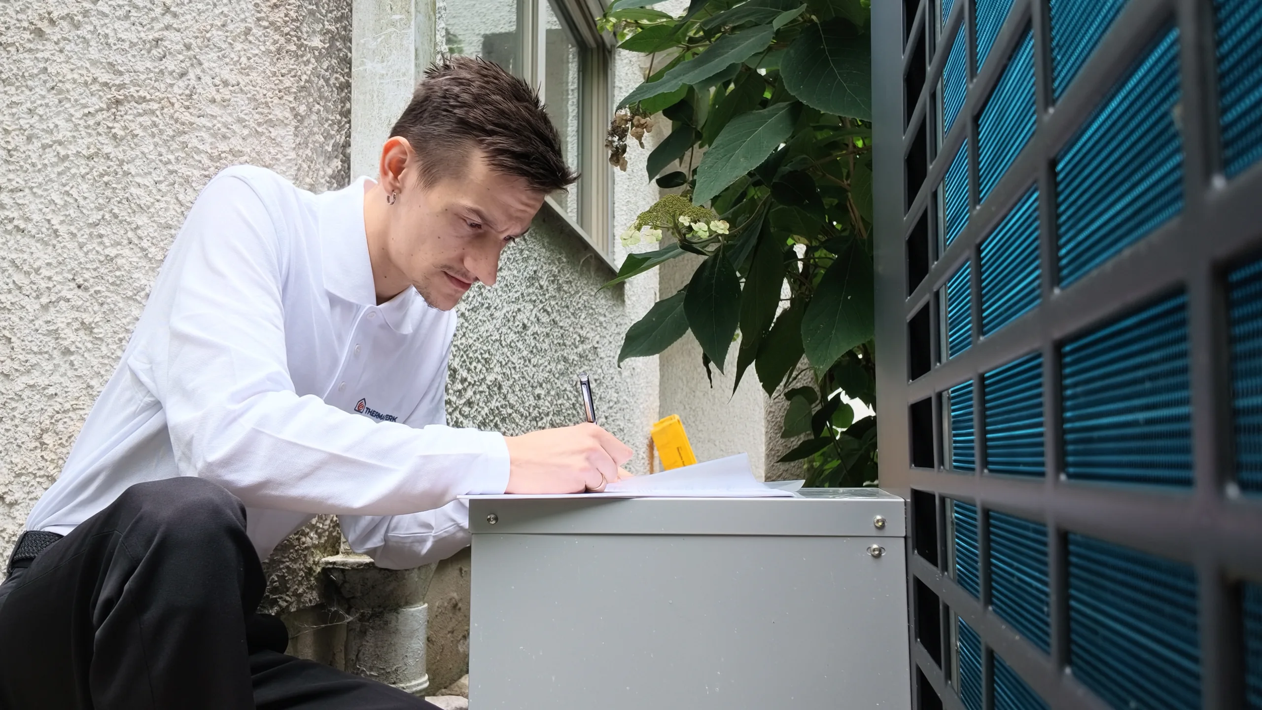 Mitarbeiter der ThermaWerk GmbH nimmt die Daten für die Heizlastberechnung an der Wärmepumpe auf