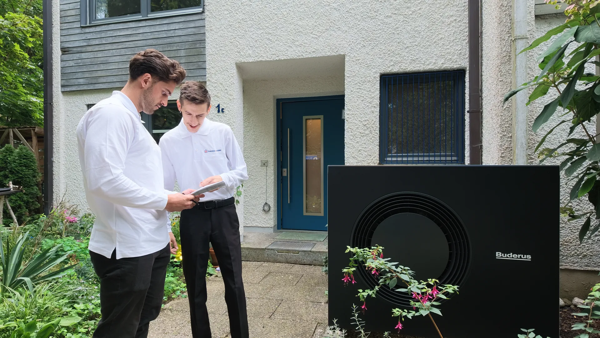 Zwei Mitarbeiter der ThermaWerk GmbH gehen gemeinsam Unterlagen an einer Wärmepumpe durch