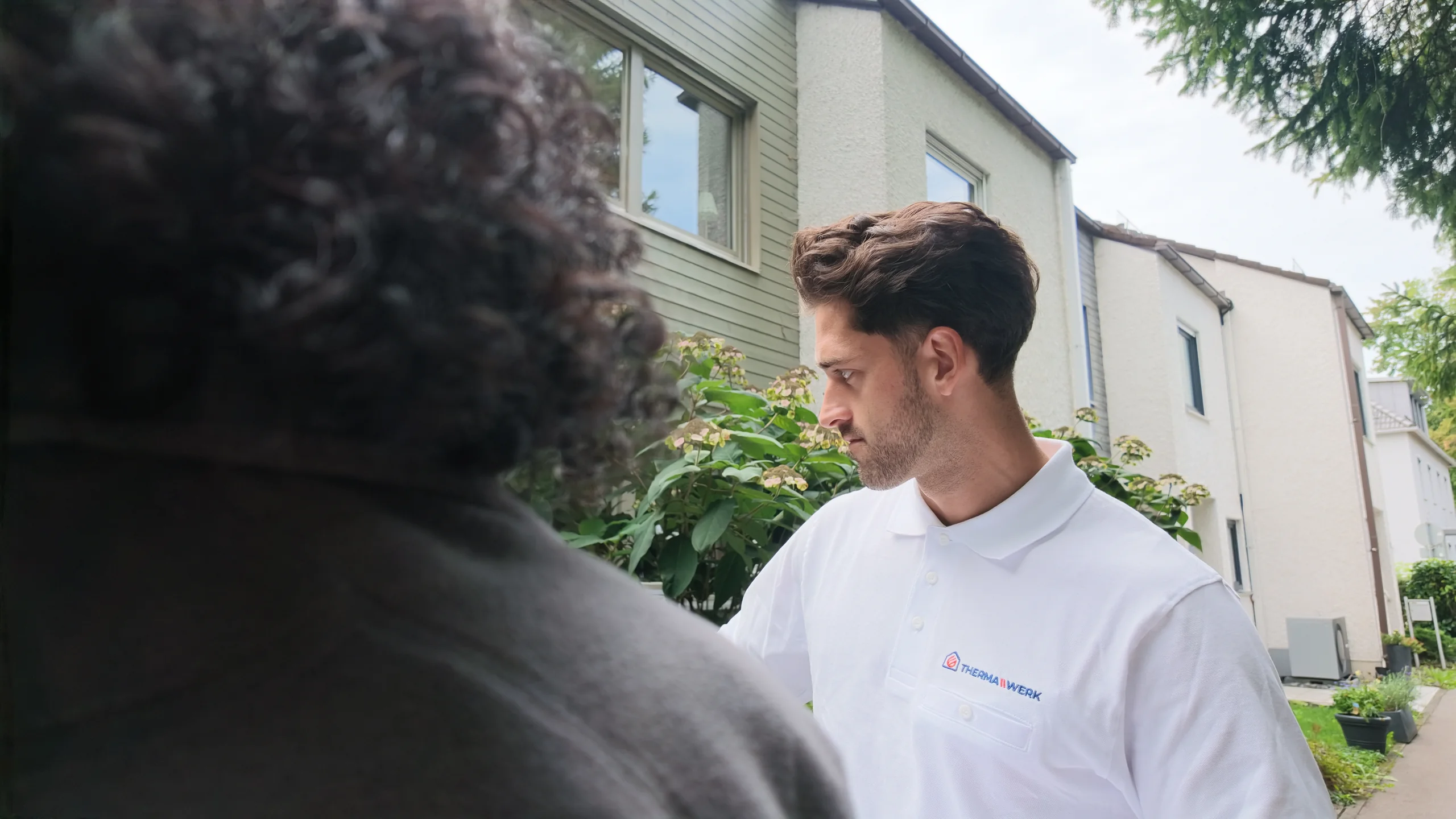 Berater der ThermaWerk GmbH im Vor-Ort-Gespräch vor einem Wohnhaus in Freising