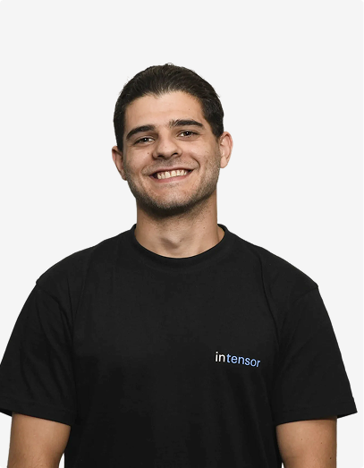 Ein lächelnder Mann mit kurzen dunklen Haaren trägt ein schwarzes T-Shirt mit dem Logo Intensor.