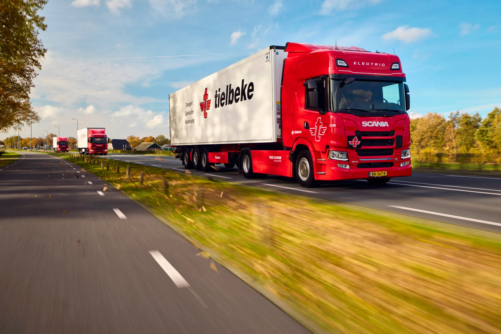 Rode elektrische Scania-vrachtwagen van Tielbeke rijdend op een provinciale weg