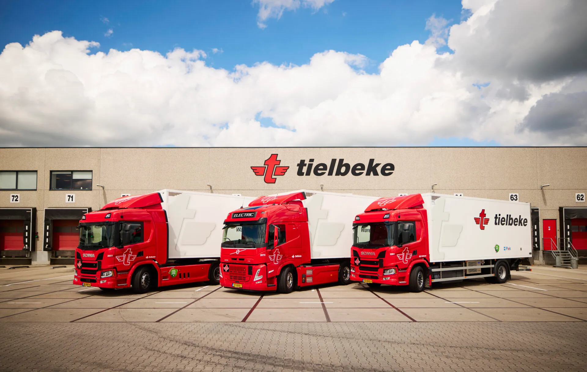 Drie rode vrachtwagens van Tielbeke bij de laaddocks van het distributiecentrum