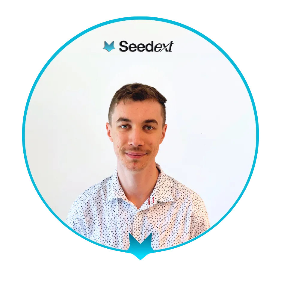 Portrait d’un homme avec une chemise à motifs blancs, souriant légèrement devant un fond blanc avec le logo Seedext.