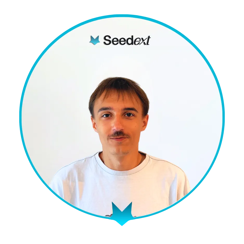 Portrait d'un homme aux cheveux bruns courts et moustache, portant un t-shirt blanc, sur fond blanc clair avec un cercle turquoise autour.