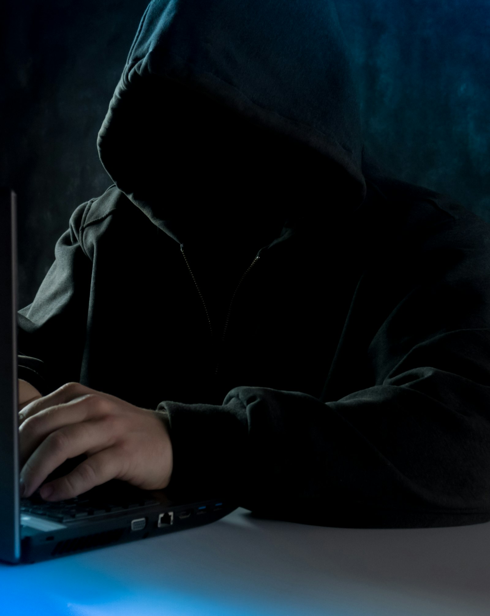 Personne travaillant sur un ordinateur portable, symbole des réseaux de fraude utilisant l'IA