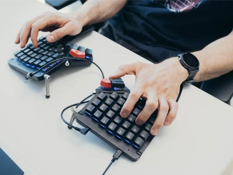 Hands typing on a split keyboard at a desk.