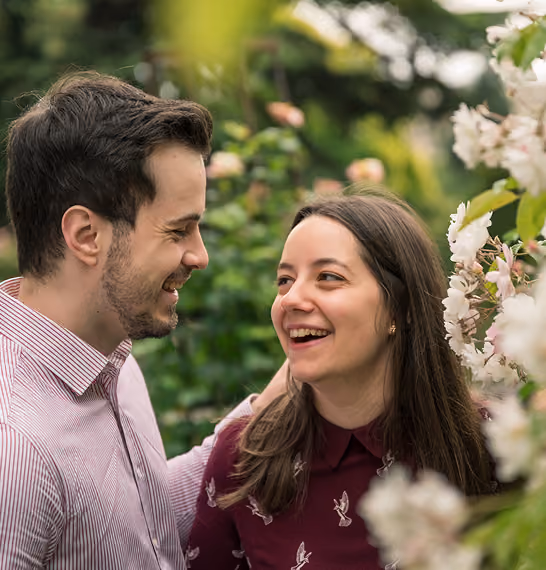 Un homme et une femme sourient en se regardant dans un jardin fleuri.