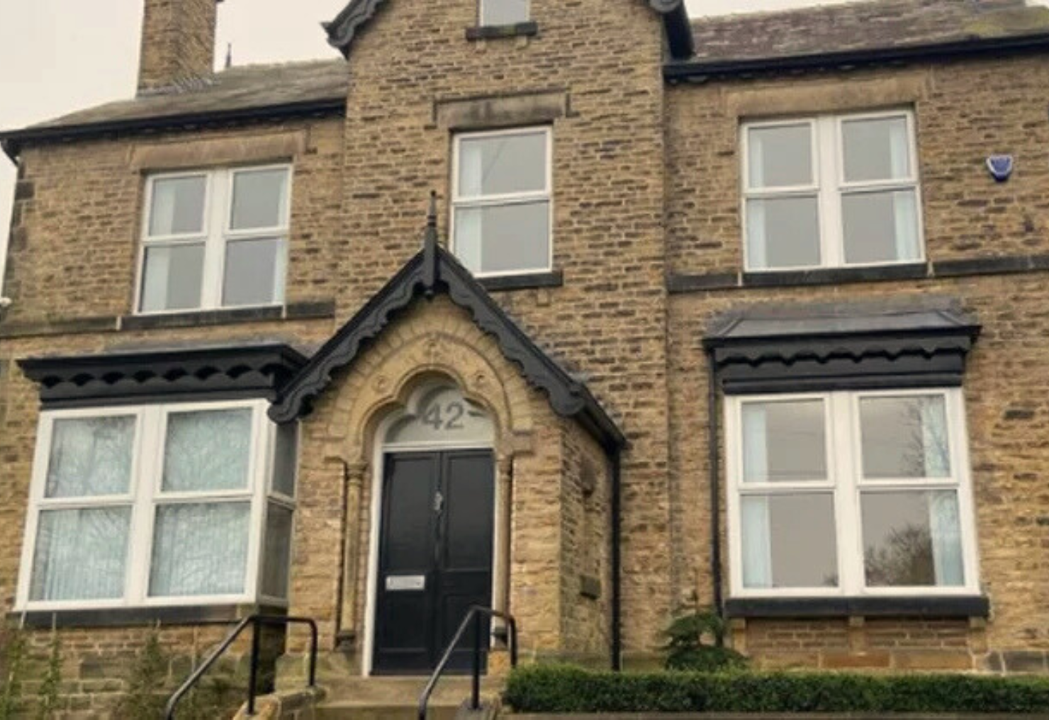 Stone house with a black door marked with number 42 and white-framed windows.