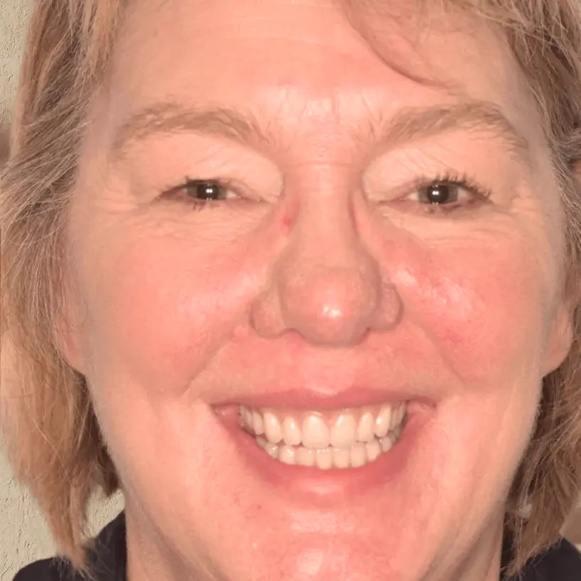 Close-up of a middle-aged woman with short light brown hair smiling, showing her teeth.