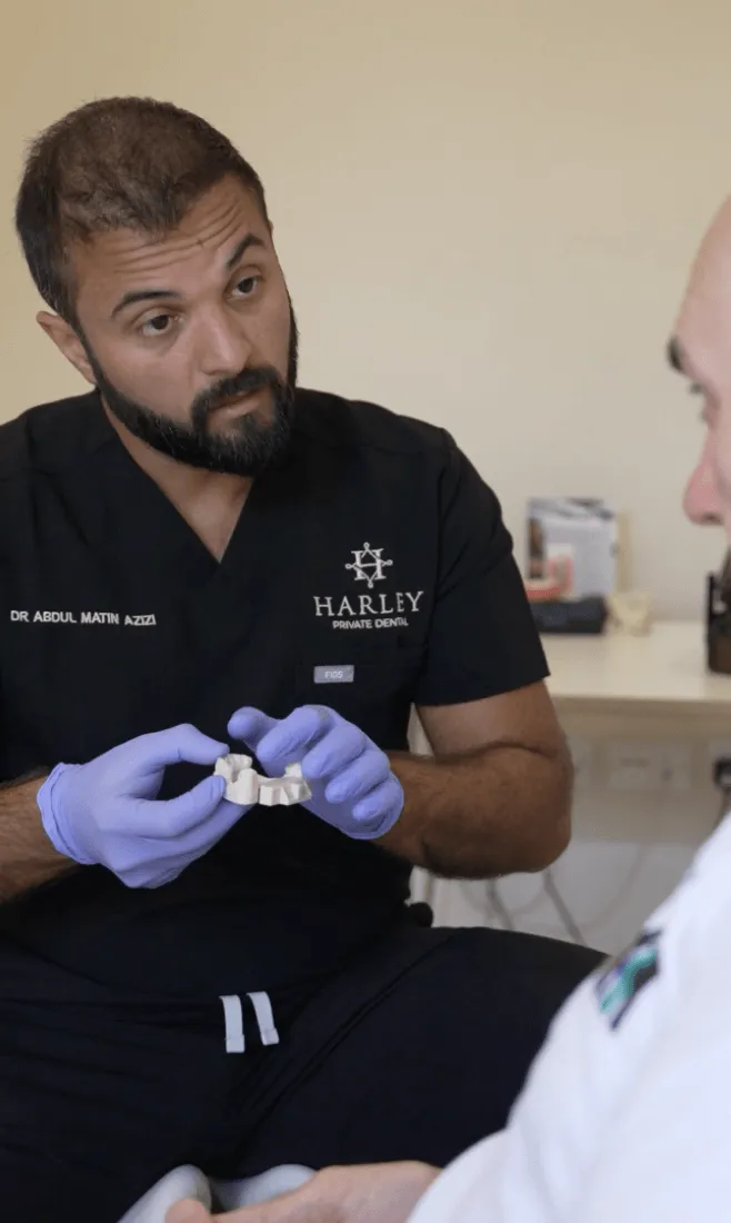 Dr Azizi explaining treatment to a patient using a dental model