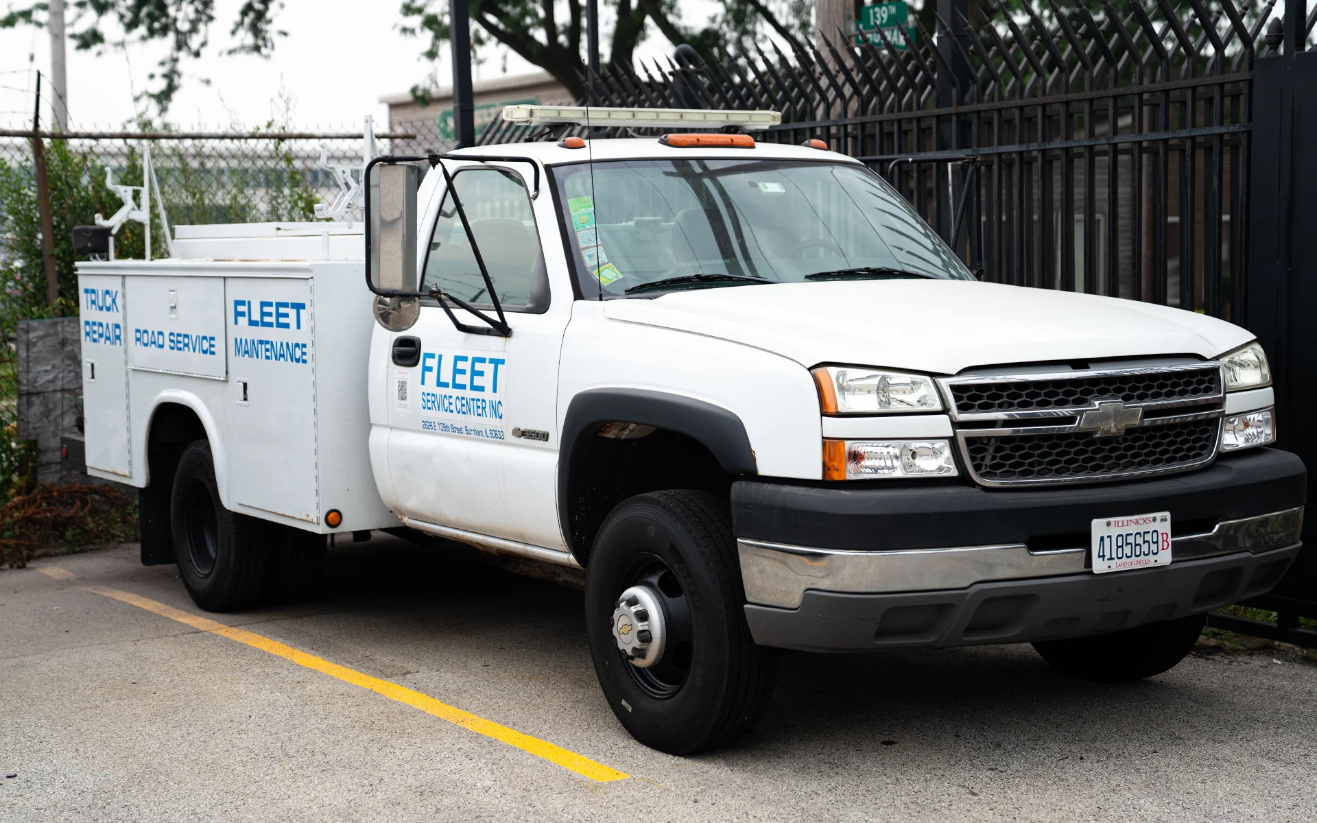 White fleet service truck parked, labeled with fleet maintenance, repair, and road service in blue text.