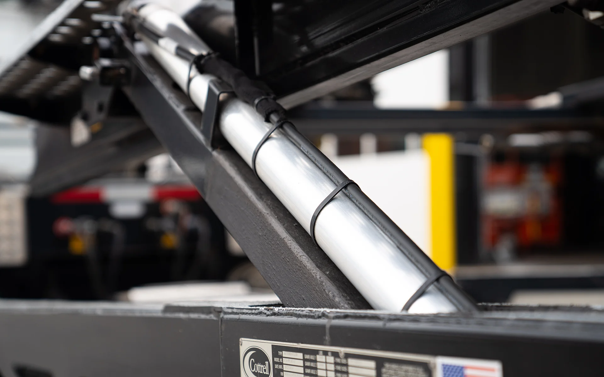 Close-up of a shiny hydraulic cylinder on heavy machinery with blurred background.
