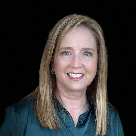 Smiling woman with straight blonde hair wearing a dark green blouse against a black background.