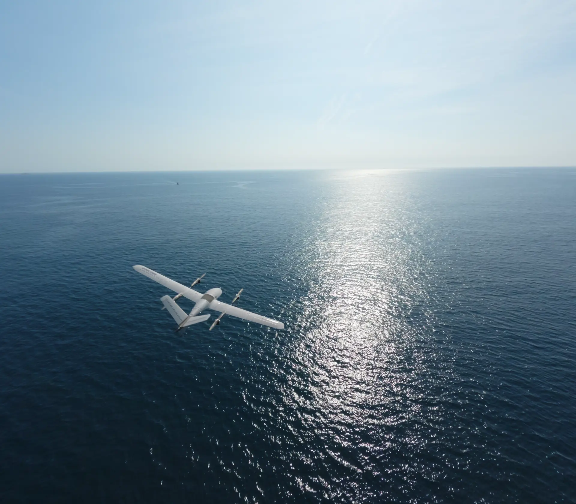 BVT516 seen from above flying low over open sea, sunlight glinting off the water towards the horizon