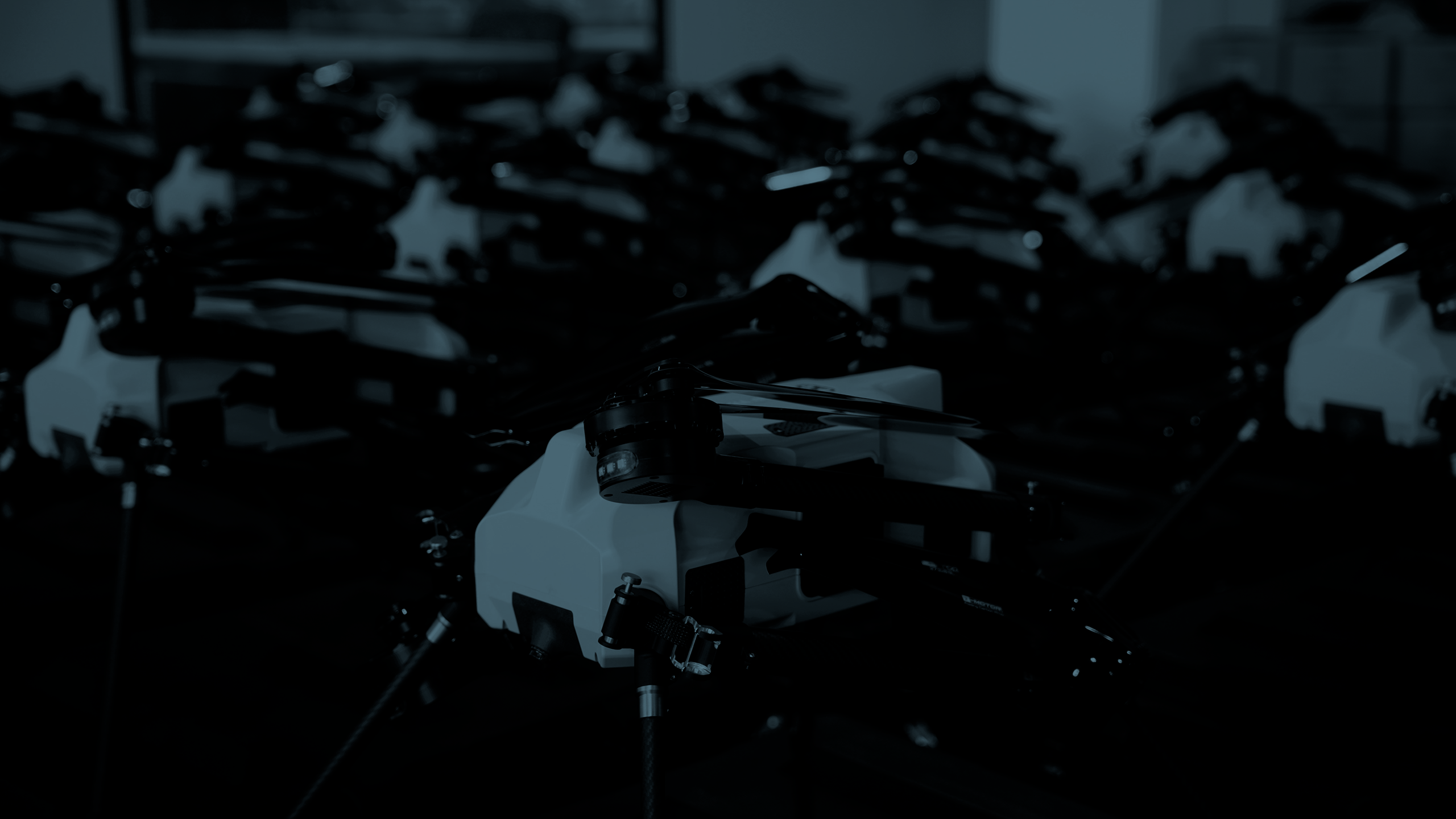 Rows of Beyond Vision quadcopters with folded arms lined up in a workshop, one in sharp focus in the foreground