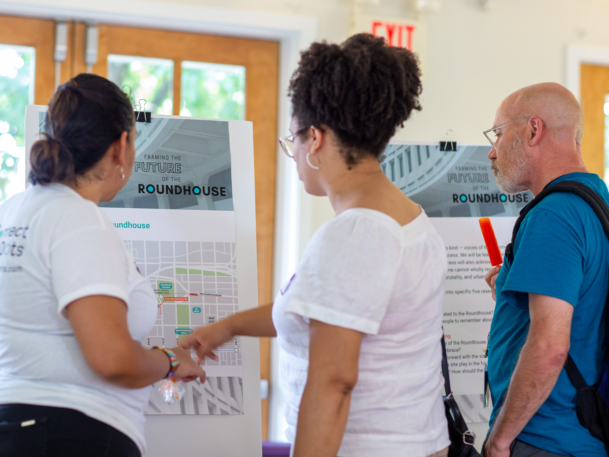 A woman points out information on a board with two other individuals