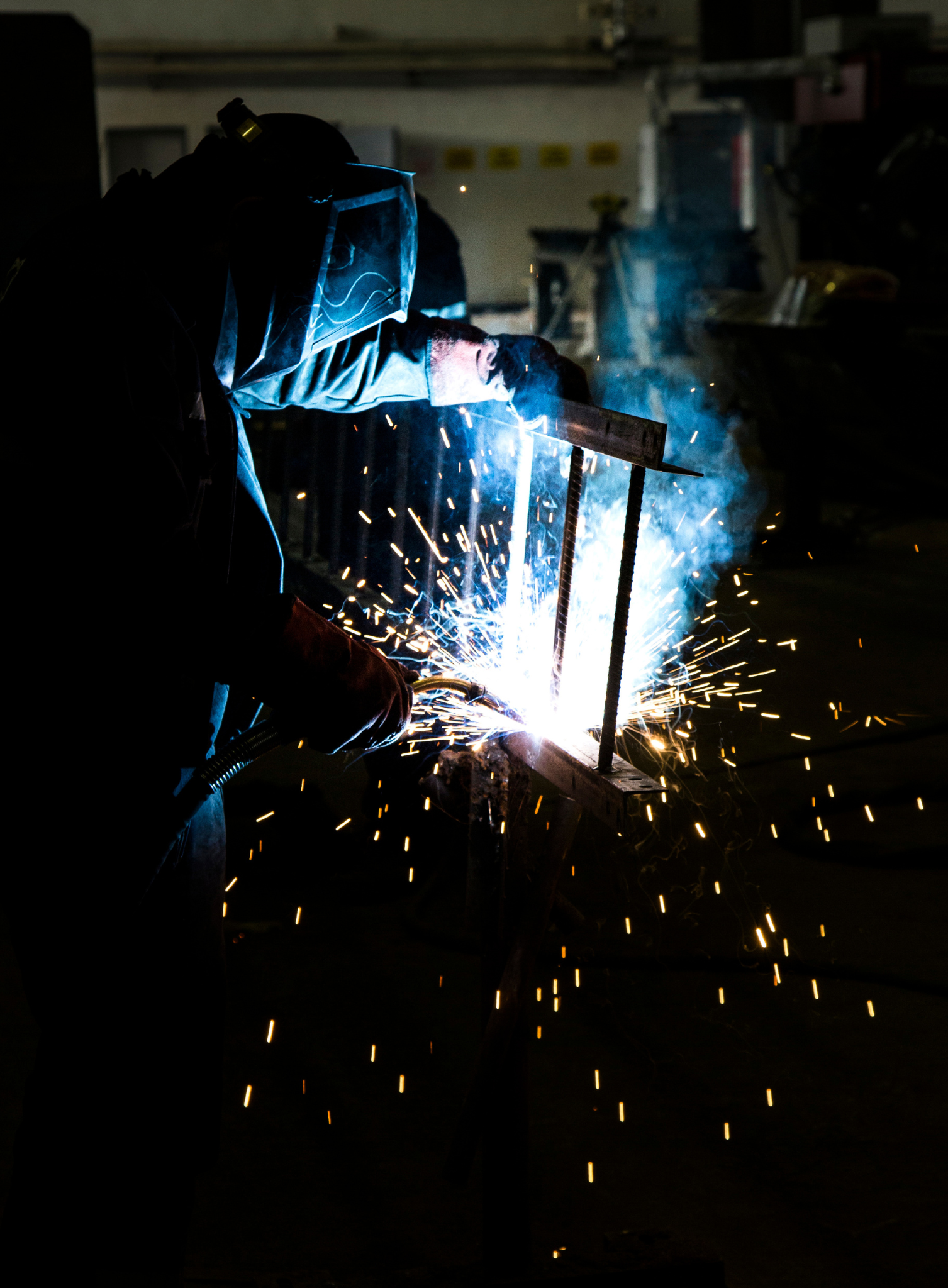 Welder fabricating a steel vessel in an industrial workshop