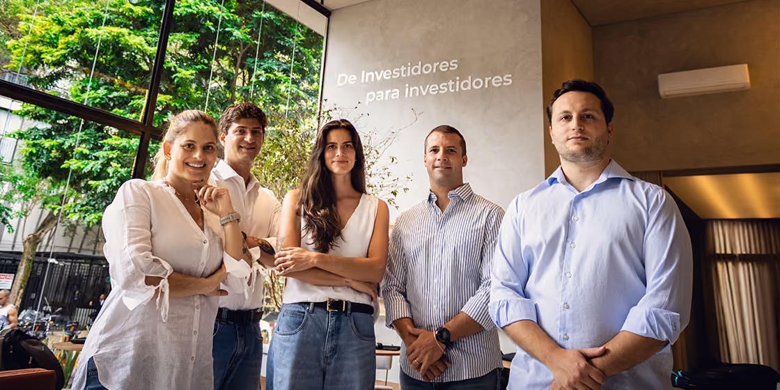 Equipe da Indepy diante do painel com a frase de investidores para investidores, na sede da incorporadora em São Paulo.