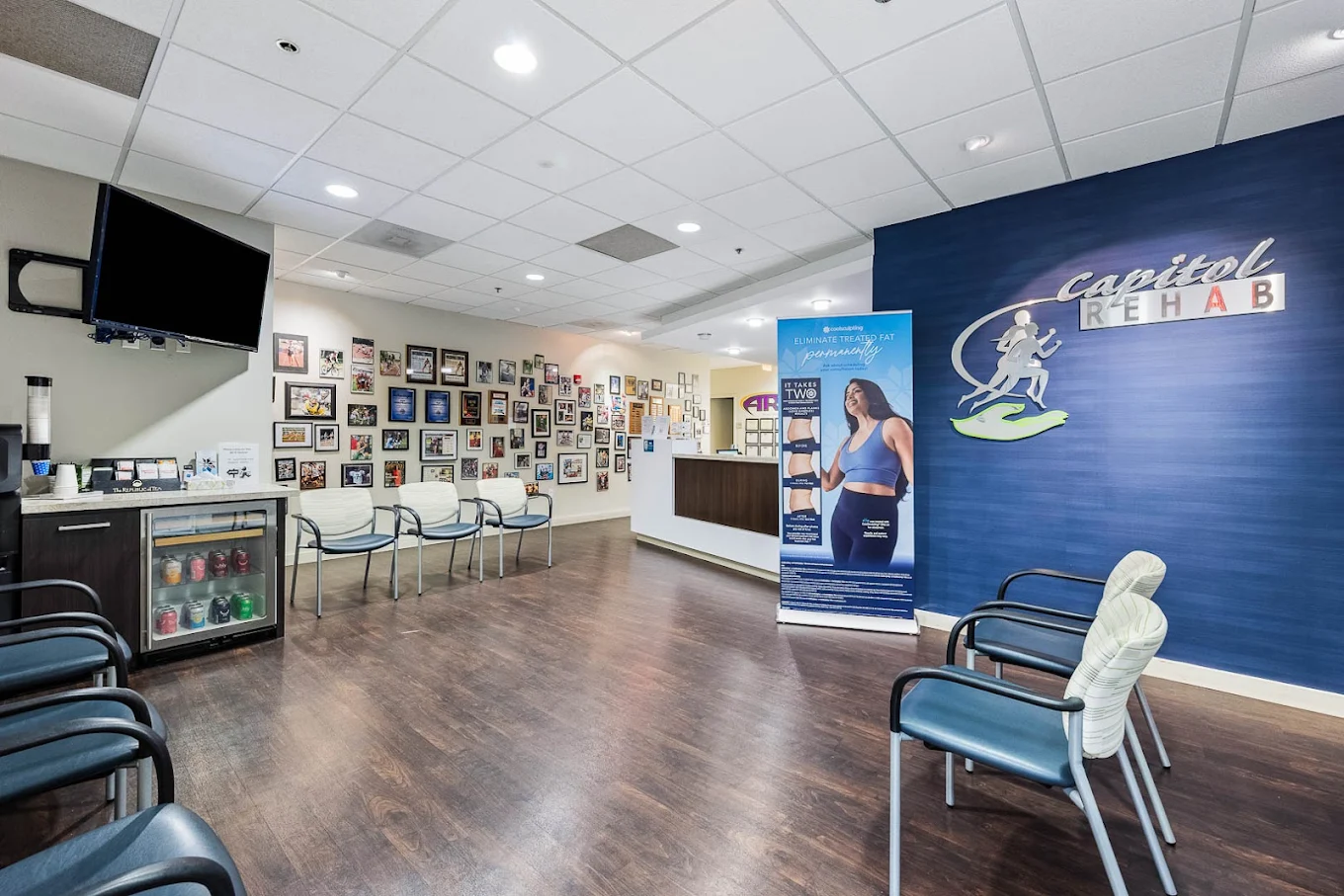 Modern gym with weight racks, exercise benches, green turf, treadmills, and sports jerseys on the wall.