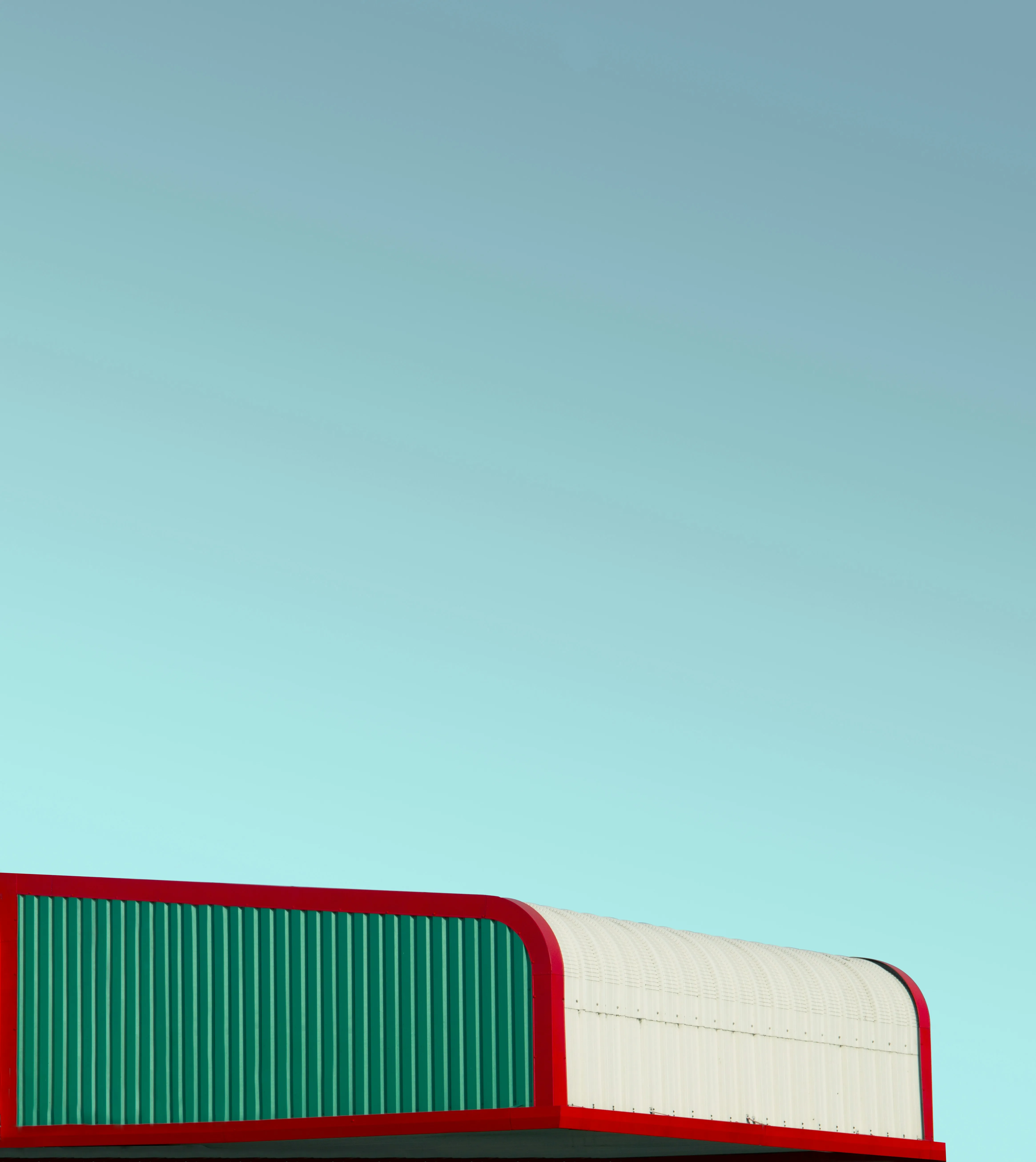 Toiture blanche et verte liserée de rouge sous un ciel turquoise