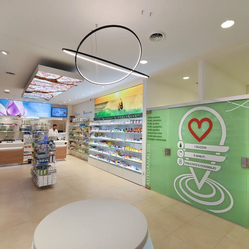 Interior of a modern pharmacy with shelves of products and a staff member at the counter.