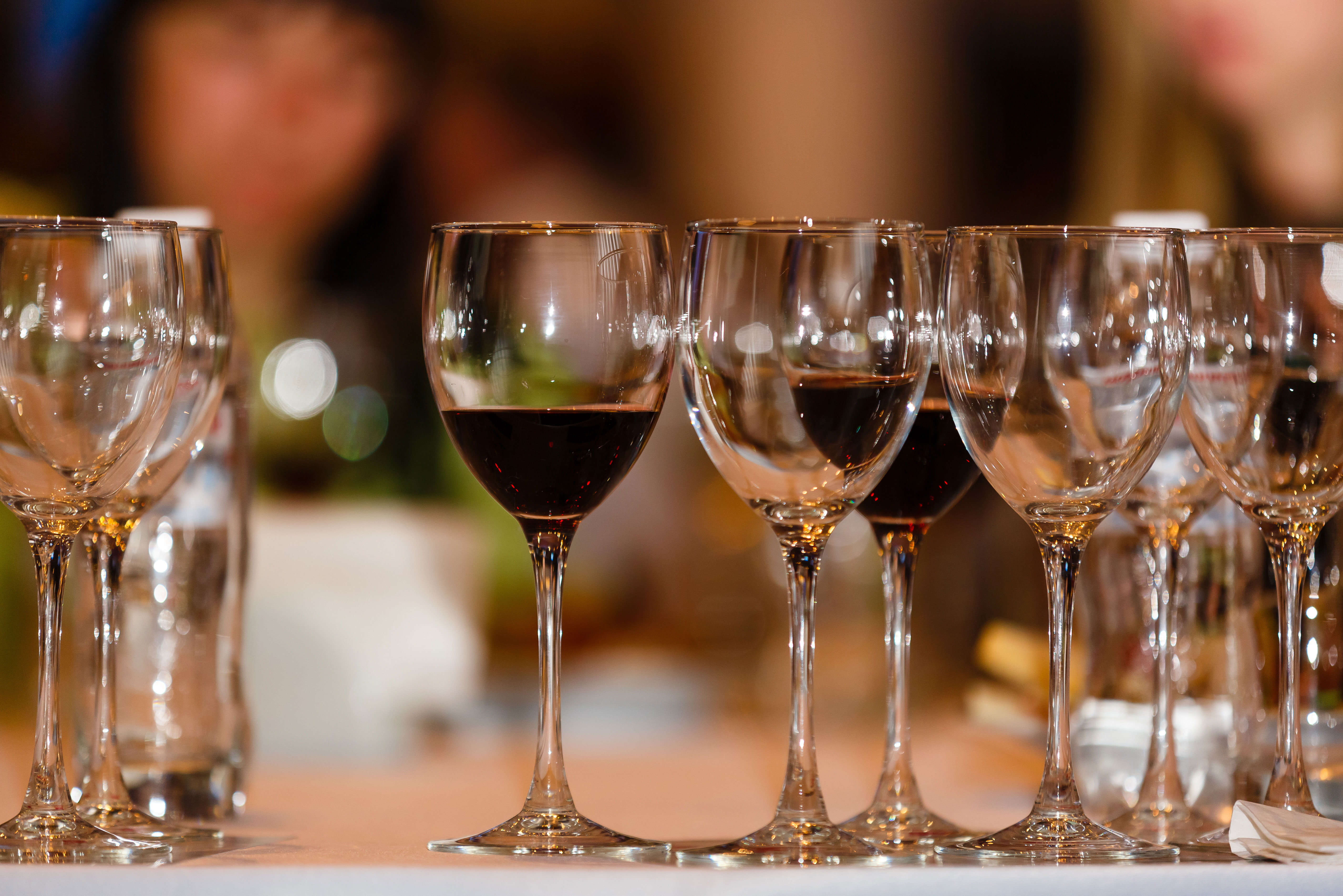 Glasses of wine on a table at a restaurant with people in the background