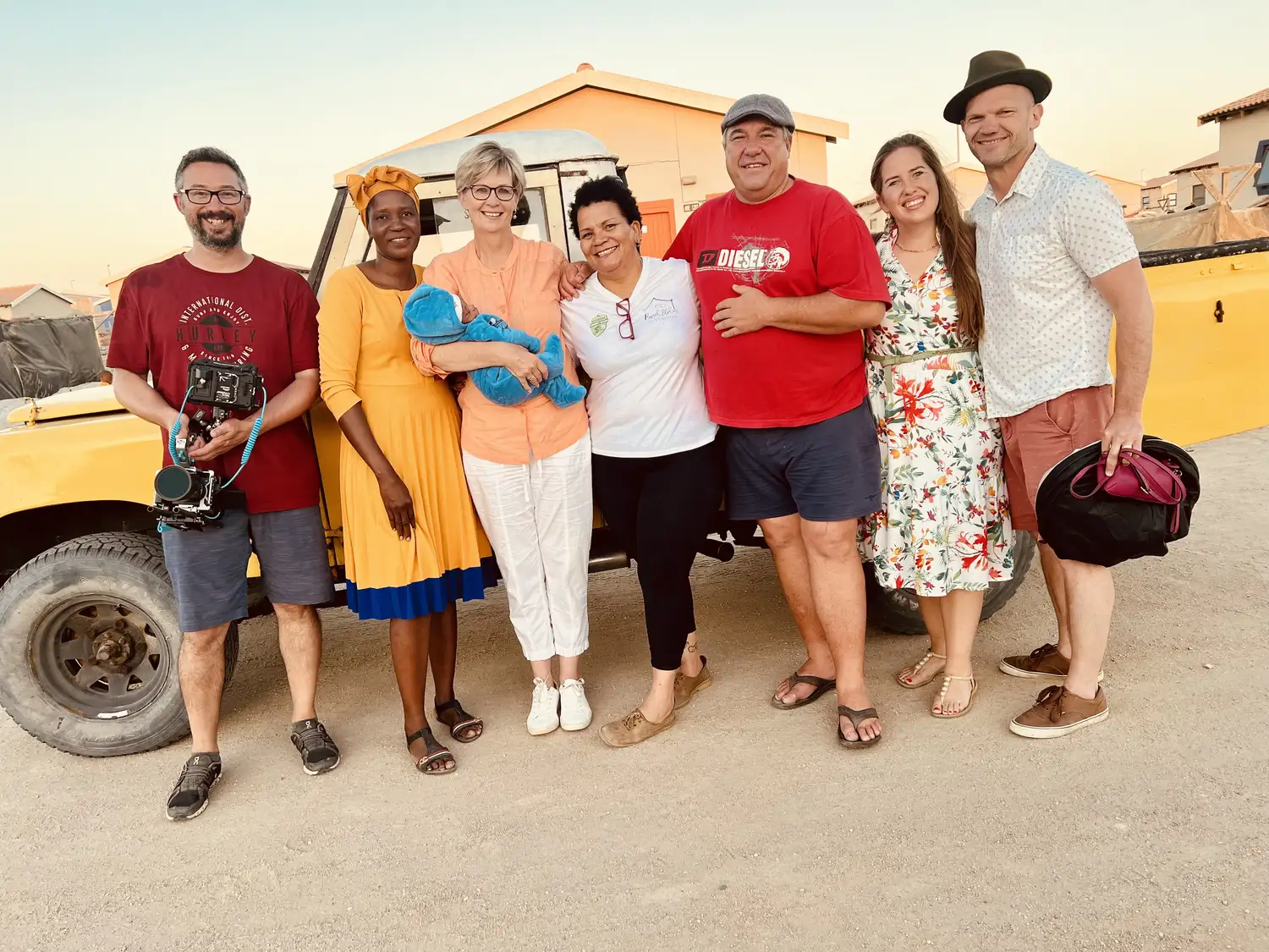 Film crew and local partners gathered beside a truck at golden hour during a documentary shoot in Namibia