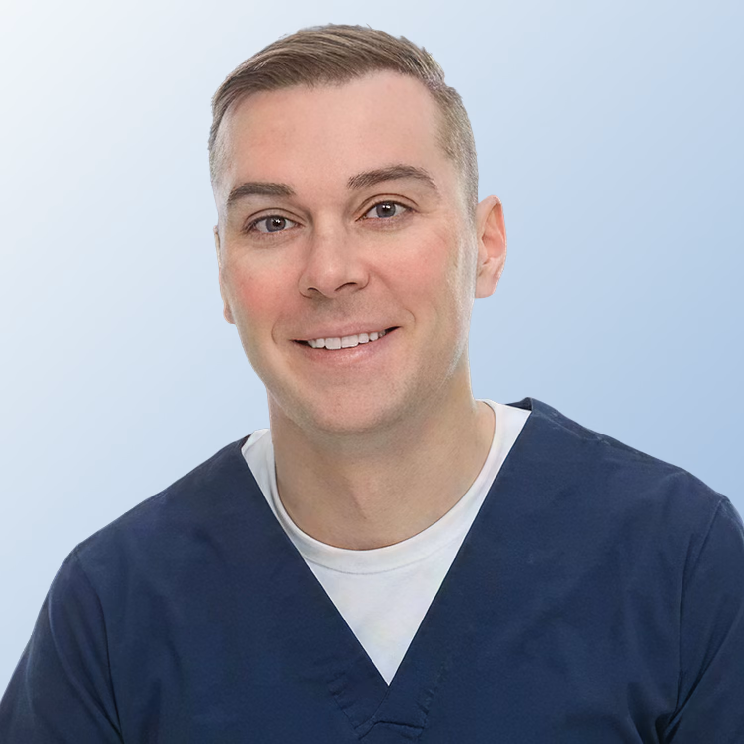 Dr. Jason Papenfuss wearing a navy blue scrub top and white undershirt.