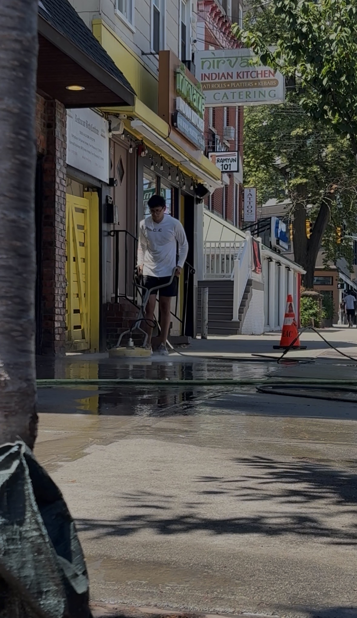 Crystal Clean Exteriors technician pressure washing a sidewalk outside a storefront