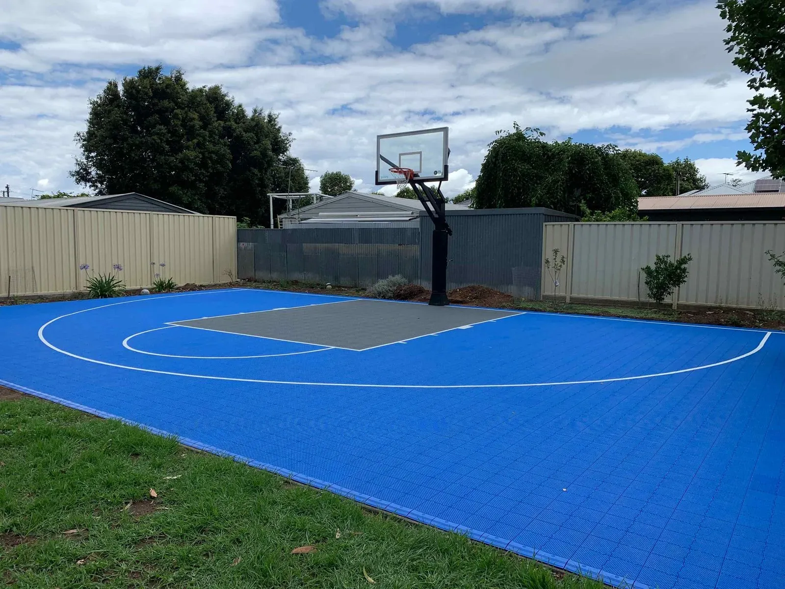 Blue basketball court in a residential backyard