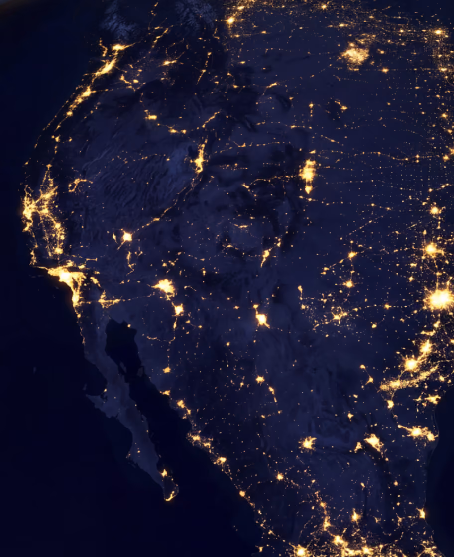 Satellite view of the western United States and Mexico at night showing city lights and road networks.