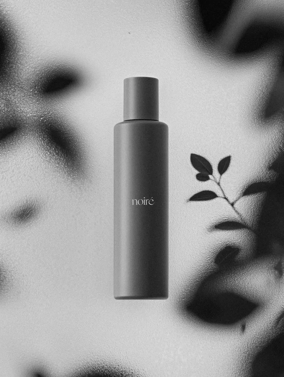 Matte black cylindrical bottle with the word 'noiré' on textured glass background.