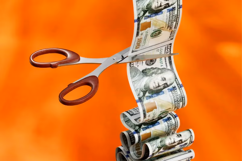 Scissors cutting printed dollar bills