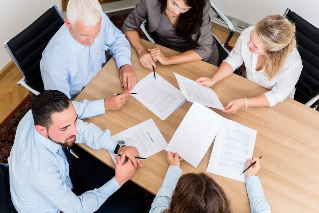 Lawyers having team meeting in law firm reading documents and negotiating agreements