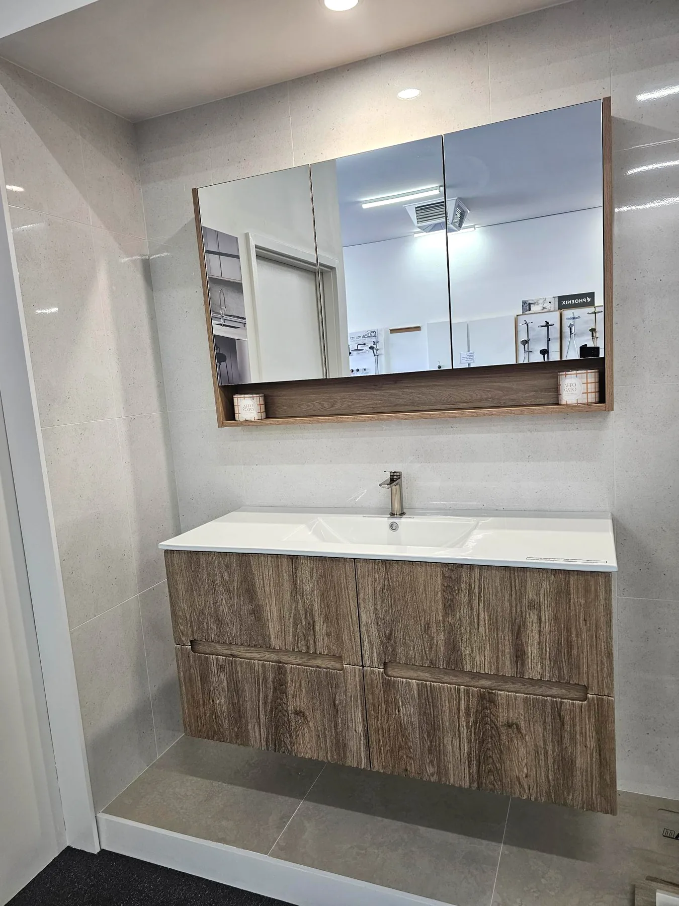 A weathered oak slab front wall hung vanity with routed finger pulls and a round mirror